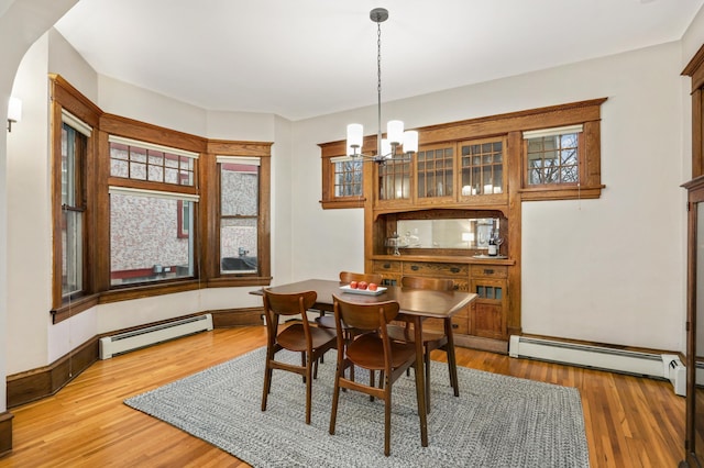 dining room with a chandelier, baseboard heating, and light wood-type flooring