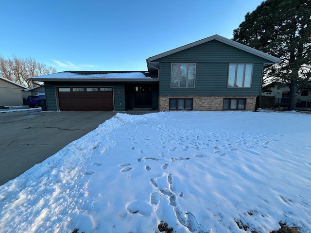 split level home featuring driveway, brick siding, and an attached garage