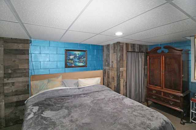 bedroom featuring concrete block wall and a paneled ceiling