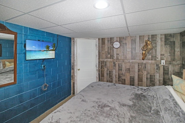 unfurnished bedroom with a drop ceiling and concrete block wall