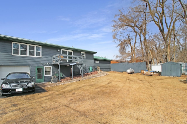 rear view of property featuring an outbuilding, a shed, an attached garage, and driveway