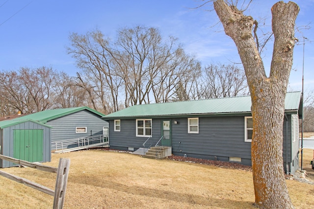 view of front of house featuring fence, metal roof, a storage shed, crawl space, and an outbuilding