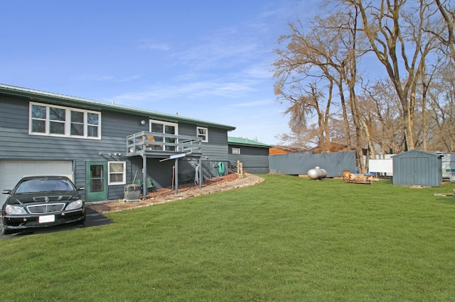 rear view of house featuring a garage, a storage unit, a wooden deck, and a lawn