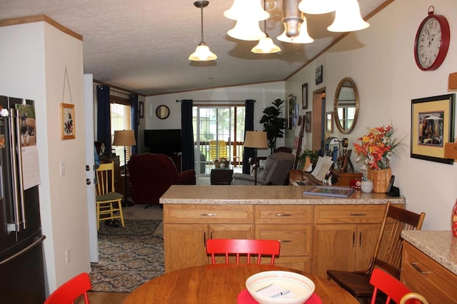 kitchen featuring a textured ceiling, open floor plan, light countertops, freestanding refrigerator, and brown cabinetry