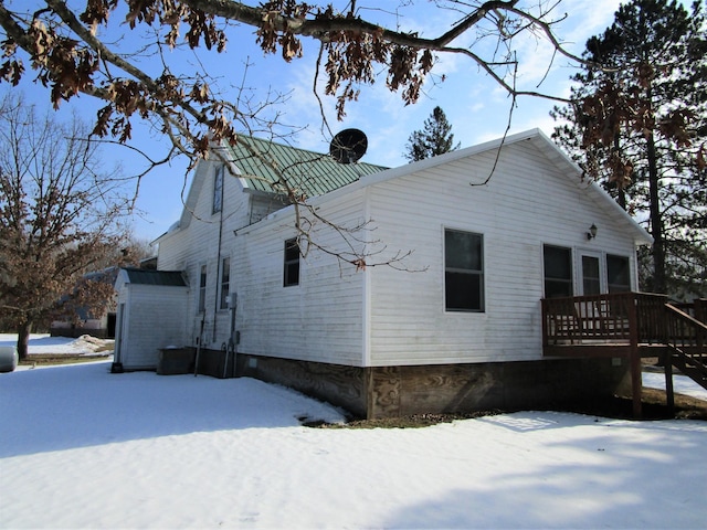 view of snowy exterior featuring a deck and metal roof