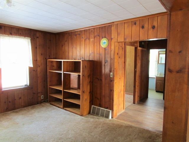 unfurnished room featuring visible vents, wood walls, and light carpet