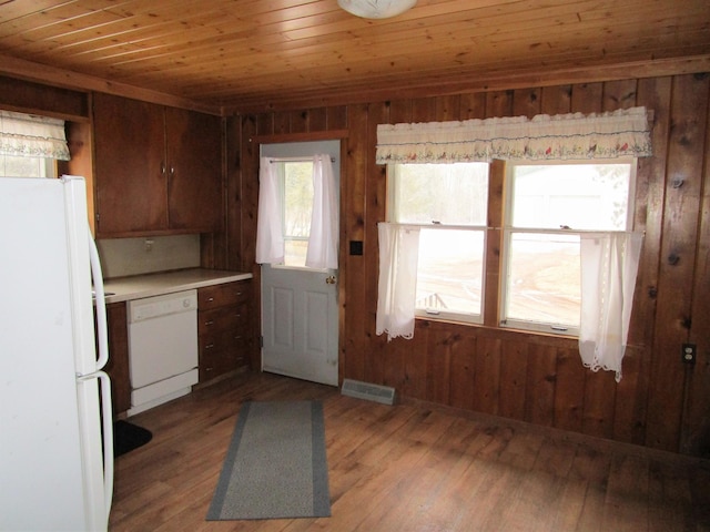 kitchen featuring white appliances, light wood finished floors, visible vents, wooden ceiling, and wood walls