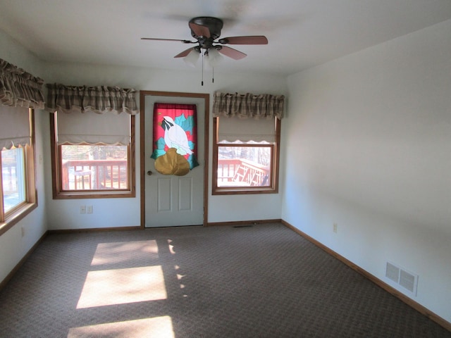 spare room with carpet floors, visible vents, baseboards, and a ceiling fan