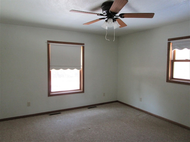 spare room with light carpet, baseboards, visible vents, and a ceiling fan