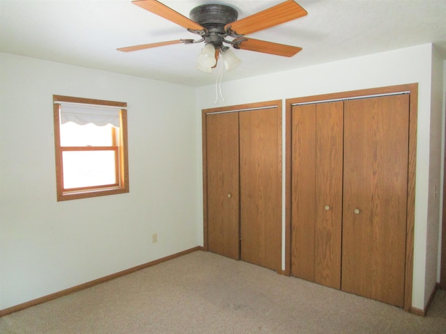 unfurnished bedroom with ceiling fan, baseboards, multiple closets, and carpet flooring