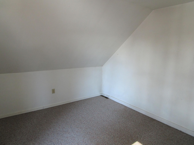 additional living space with lofted ceiling, baseboards, and dark carpet