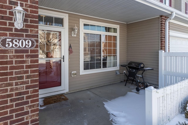 entrance to property featuring a garage and brick siding