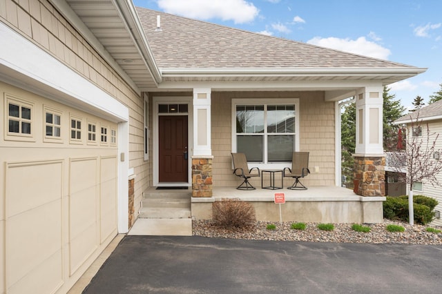 3595 Lemieux Cir, Eagan, MN 55122 - view of exterior entry with covered porch, a shingled roof, driveway, and stone siding