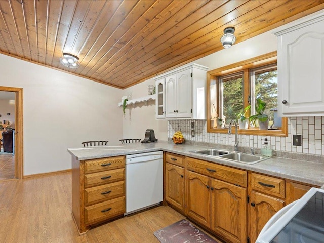 kitchen featuring decorative backsplash, dishwasher, a peninsula, and a sink