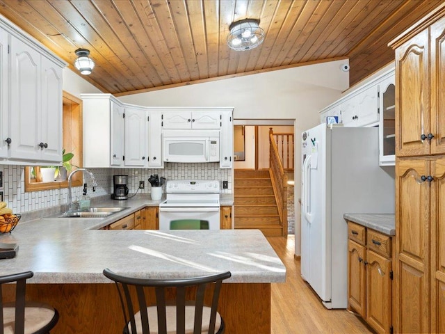 kitchen featuring tasteful backsplash, a sink, white appliances, a peninsula, and a kitchen bar