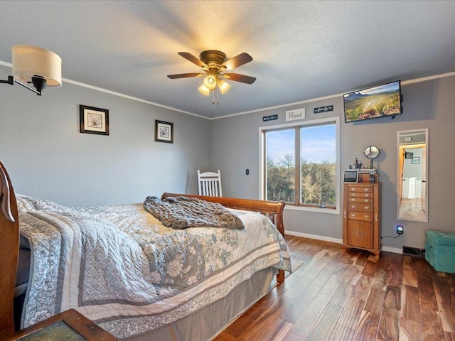 bedroom with a textured ceiling, baseboards, wood finished floors, and crown molding