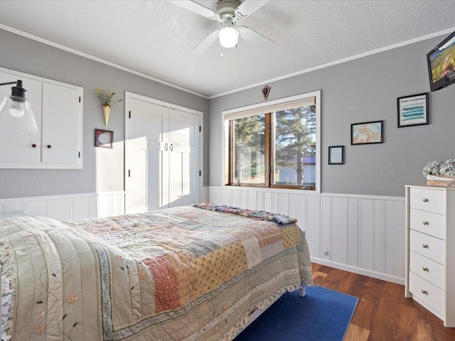 bedroom featuring a textured ceiling, ornamental molding, and wainscoting