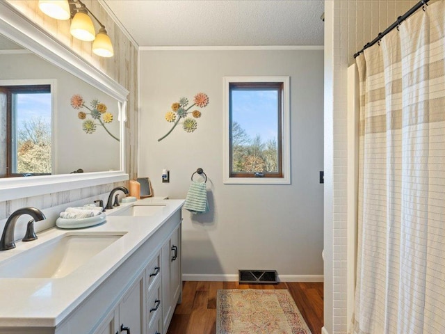 full bath featuring ornamental molding, wood finished floors, a sink, and visible vents