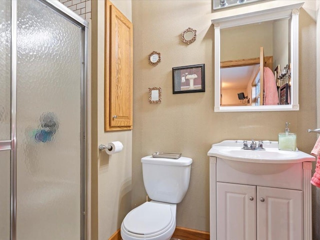 bathroom with toilet, a stall shower, and vanity