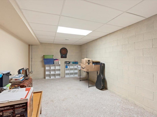 interior space with a paneled ceiling, carpet, and concrete block wall