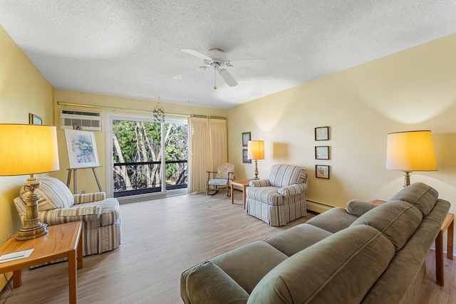 living area with ceiling fan, wood finished floors, baseboard heating, a textured ceiling, and a wall mounted AC