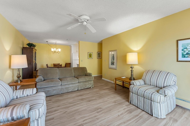 living area featuring a textured ceiling, ceiling fan with notable chandelier, light wood-type flooring, and baseboards