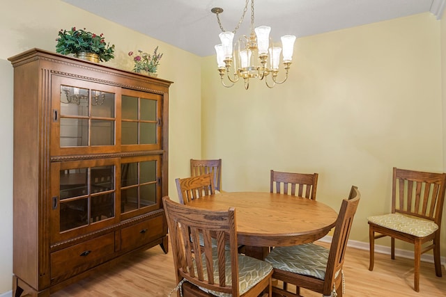 dining room with baseboards, a notable chandelier, and light wood-style floors