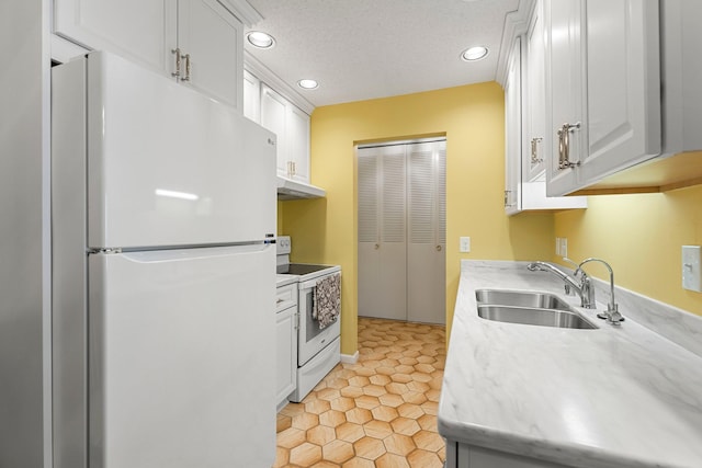 kitchen with a textured ceiling, under cabinet range hood, white appliances, a sink, and white cabinets