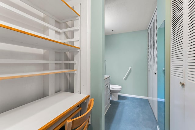 bathroom with baseboards, vanity, and toilet