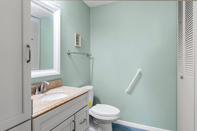 half bathroom featuring toilet, baseboards, and vanity