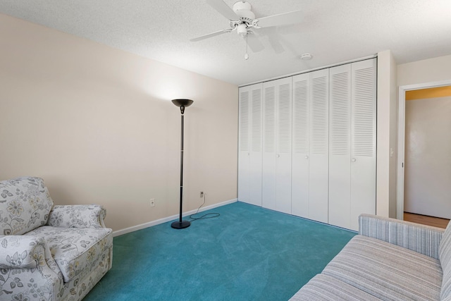 living area featuring carpet floors, ceiling fan, a textured ceiling, and baseboards