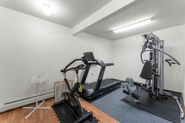 workout area with a textured ceiling, a baseboard radiator, and wood finished floors