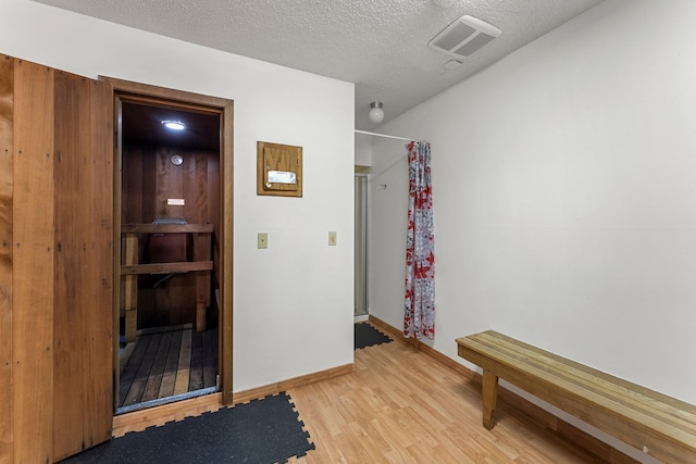 interior space with light wood-type flooring, visible vents, a textured ceiling, and baseboards