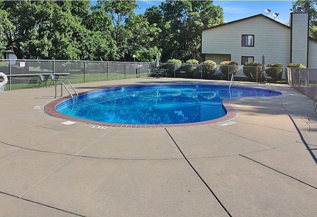 pool with a patio area and fence