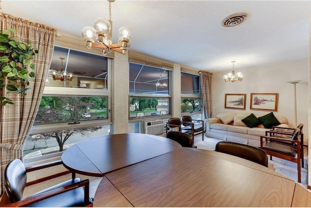 dining area featuring visible vents, an inviting chandelier, a wall of windows, a textured ceiling, and a wall mounted AC