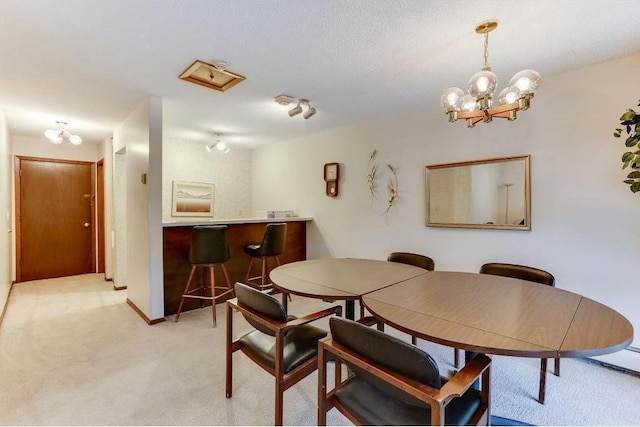 dining room with baseboards, light colored carpet, a textured ceiling, a bar, and a chandelier