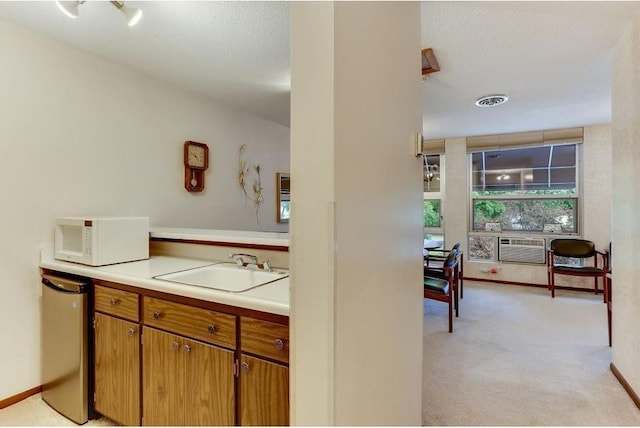 kitchen featuring refrigerator, visible vents, white microwave, light carpet, and a sink