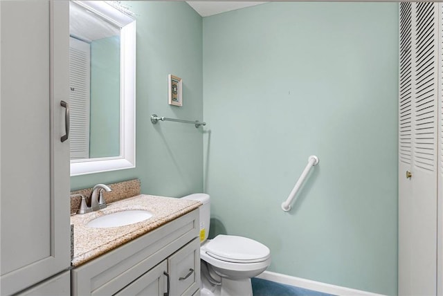 bathroom with toilet, vanity, and baseboards