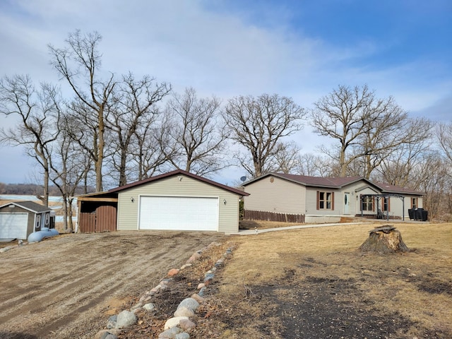 ranch-style house with an outbuilding, a garage, fence, driveway, and a carport