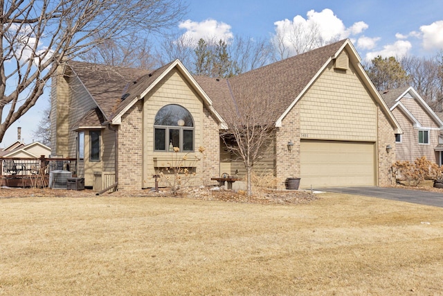 view of front facade featuring central air condition unit, driveway, roof with shingles, a wooden deck, and brick siding