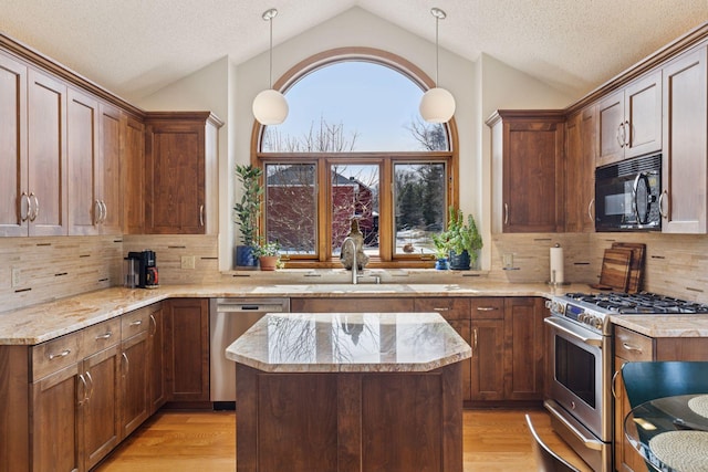 kitchen featuring light wood finished floors, vaulted ceiling, appliances with stainless steel finishes, and a sink