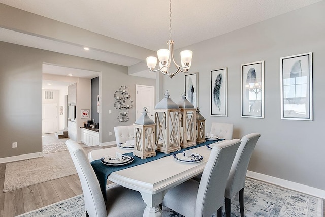 dining space with light wood-style floors, a notable chandelier, and baseboards