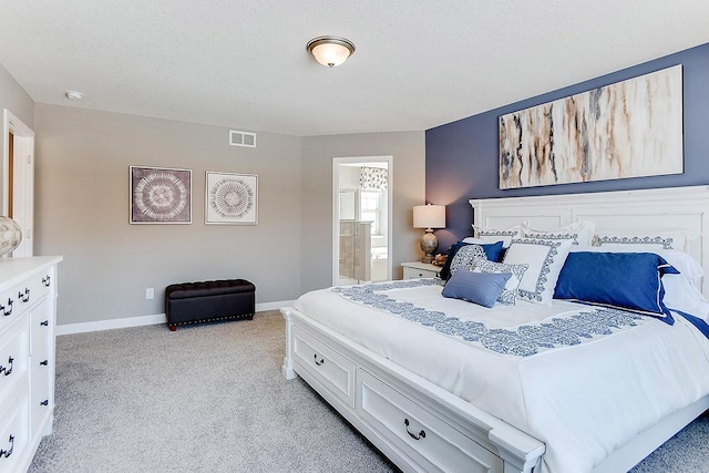 bedroom with a textured ceiling, ensuite bathroom, light carpet, visible vents, and baseboards