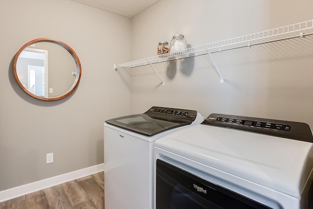 laundry area with a textured ceiling, laundry area, wood finished floors, baseboards, and independent washer and dryer