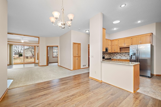 kitchen with tasteful backsplash, light wood-style flooring, stove, open floor plan, and stainless steel refrigerator with ice dispenser