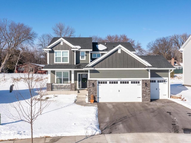 craftsman house featuring aphalt driveway, a garage, covered porch, stone siding, and board and batten siding