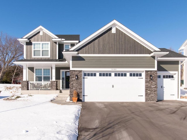 craftsman house with a porch, board and batten siding, a garage, stone siding, and driveway