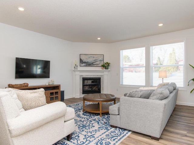 living area featuring recessed lighting, baseboards, a tiled fireplace, and light wood finished floors