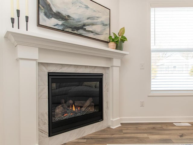 details featuring wood finished floors, a tile fireplace, visible vents, and baseboards