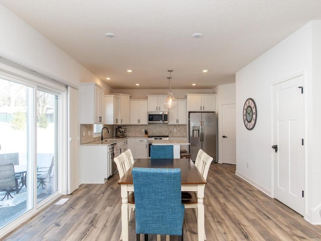 dining area featuring recessed lighting, light wood-style flooring, and baseboards